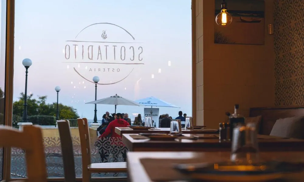 The indoor dining area and views of the Mediterranean Sea at Osteria Scottadito, Nadur.