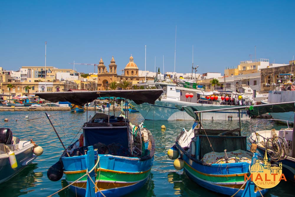 Maltese luzzu boats sailing along Marsaxlokk harbour.